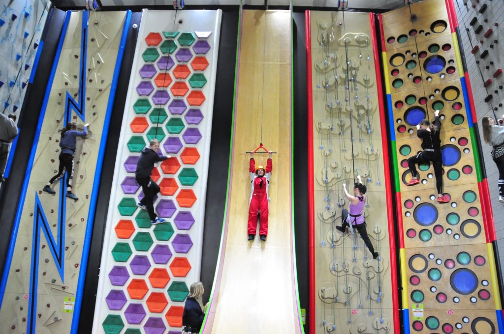 Clip n climb walls inside RockReef climbing centre in Bournemouth with a few figures climbing the walls in a line