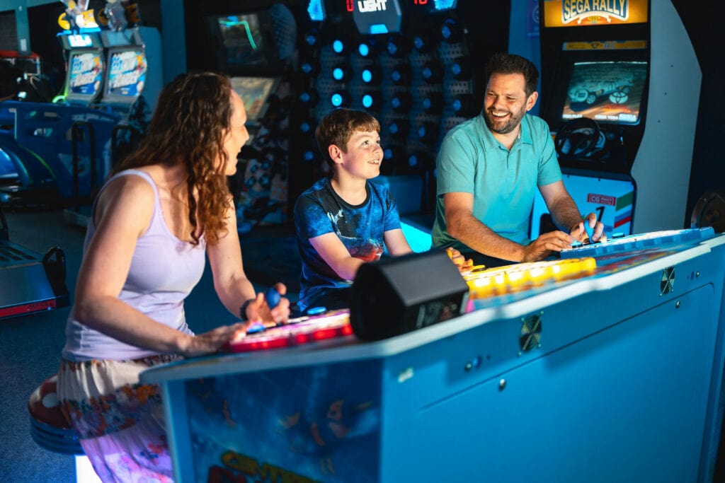 a woman, young boy and man playing an arcade game in an amusement arcade