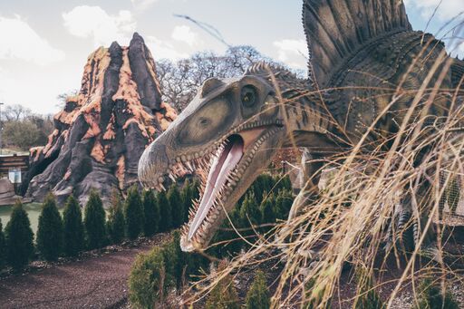 Closeup of a model dinosaur with its mouth open in front of a model volcano at Mighty Adventures Crazy golf bournemouth