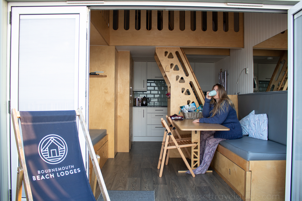 Blond girl drinking coffee in a beach hut