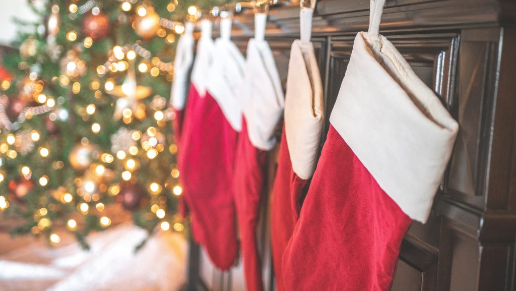 stockings on a fireplace in a row with a christmas tree in the background