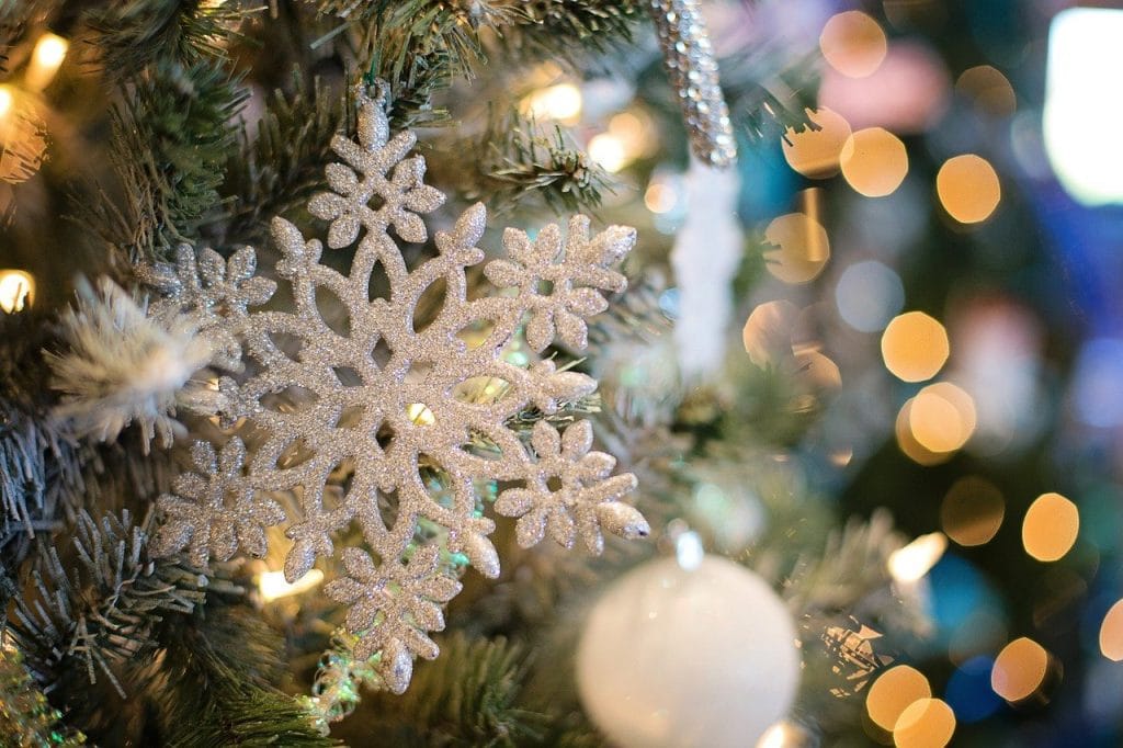 Close up of a white glittery snowflake decoration on a christmas tree with fairy lights out of focus behind. Christmas Events in Dorset