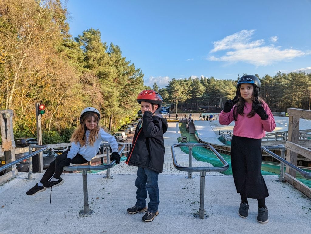 3 children standing in front of the Ringos dry ski slope at Snowtrax Christchurch