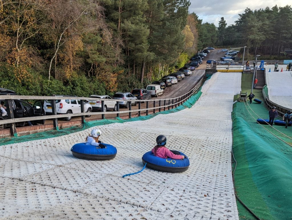 2 girls sitting in Ringos tyres to ride down a dry ski slope