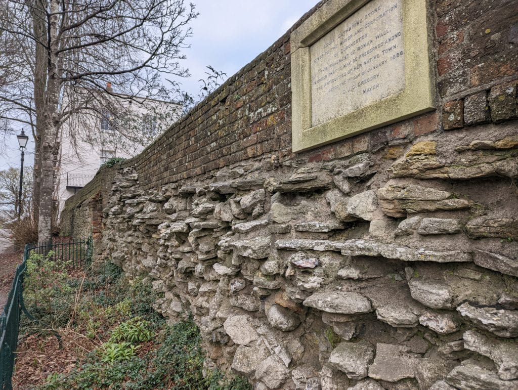 very old stone wall with a plack on a grey day