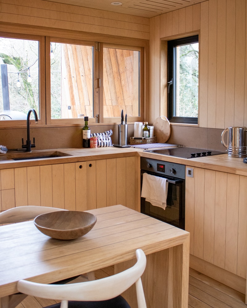 kitchen in a log cabin with wood pannelled cupboards and walls