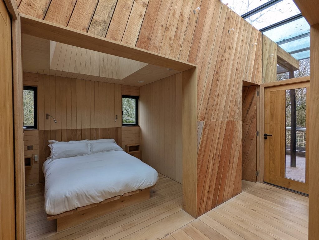 interior of a log cabin with wood panels on the walls and floors and a bed with white sheets