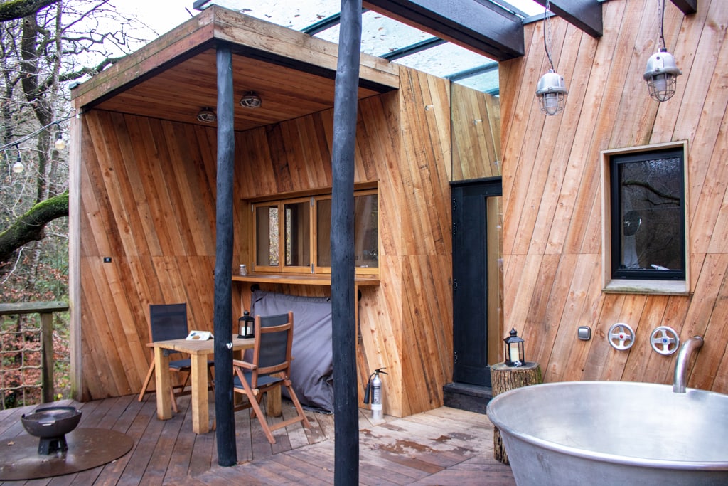 Decking at the back of Dazzle treehouse with a tin hottub and wooden posts in Dorset