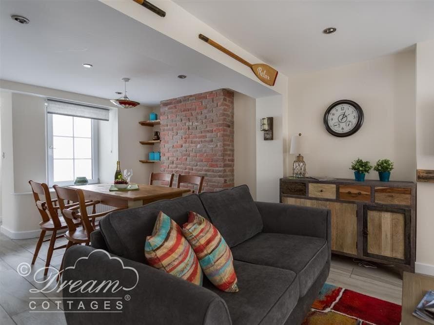a living room with white walls and an exposed brick wall and a grey fabric soda 