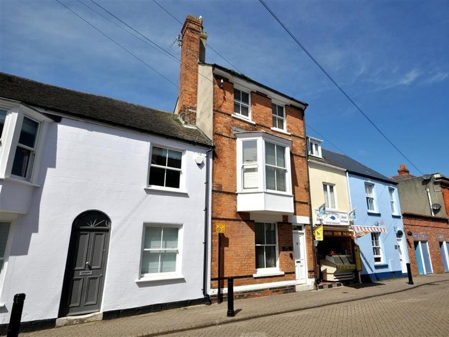 a row of terraced houses on a stone street in front of a blue sky