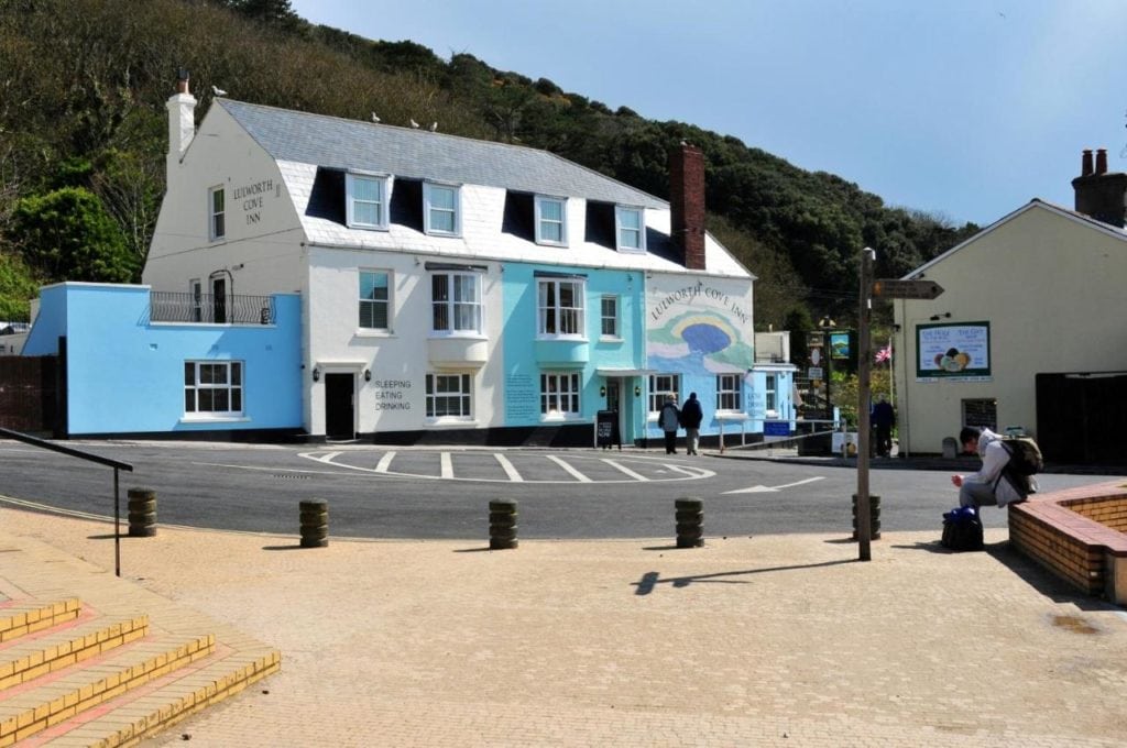 white and blue painted pub exterior with a sign saying Lulworth Cove Inn - best coastal hotels in Dorset