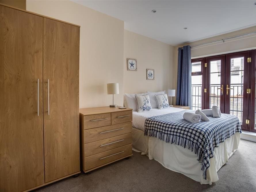 a bedroom with pine wardrobe and chest of drawers next to a double bed with a blue throw