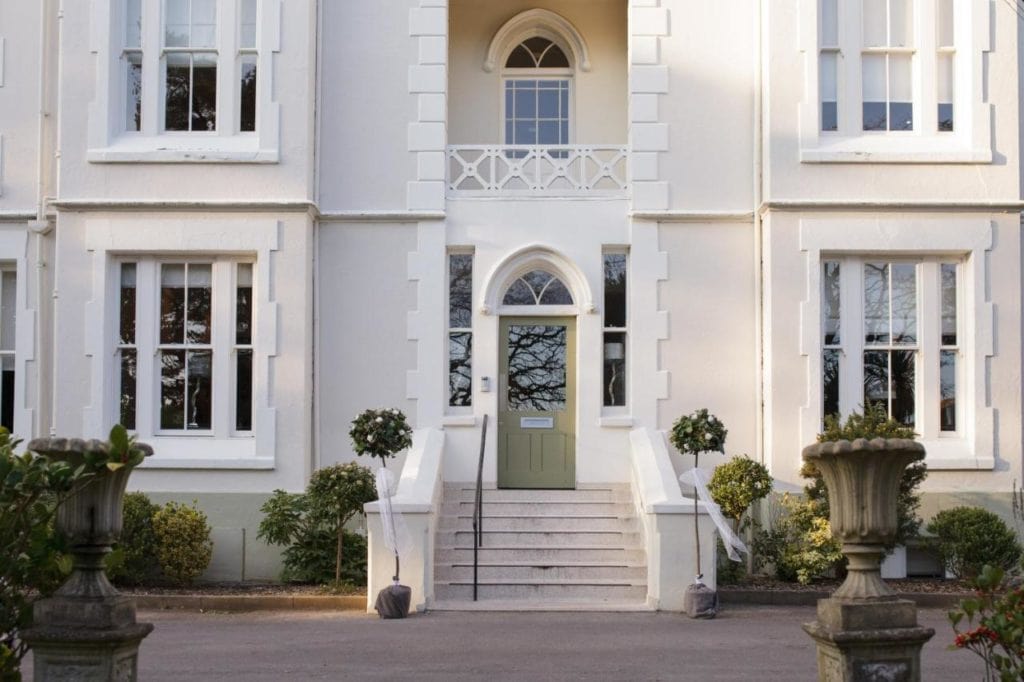 Front f a white manor in Bournemouth with a green front door - coastal hotels in dorset