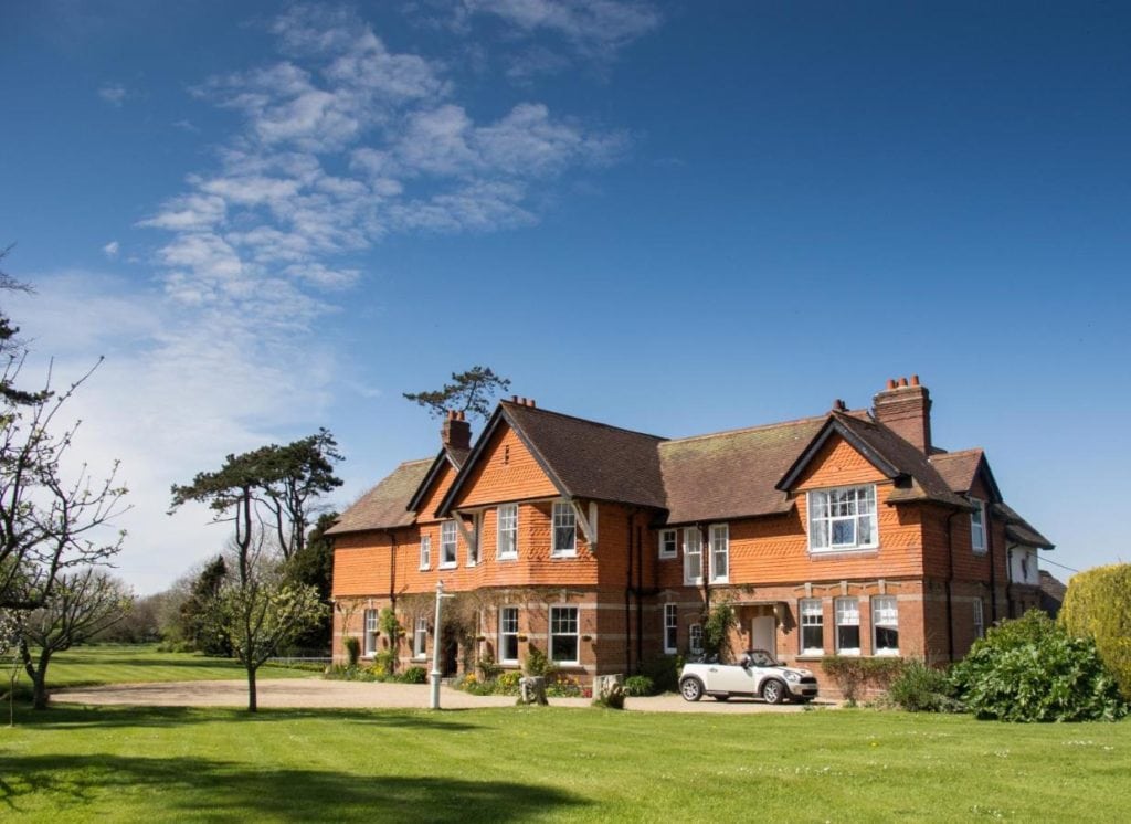 large red brick country manor with a green lawn in front under a blue sky - dog friendly hotels dorset