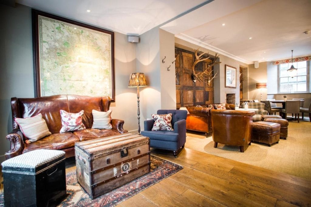 cosy pub lounge with a wooden floor, white walls, and several leather sofas