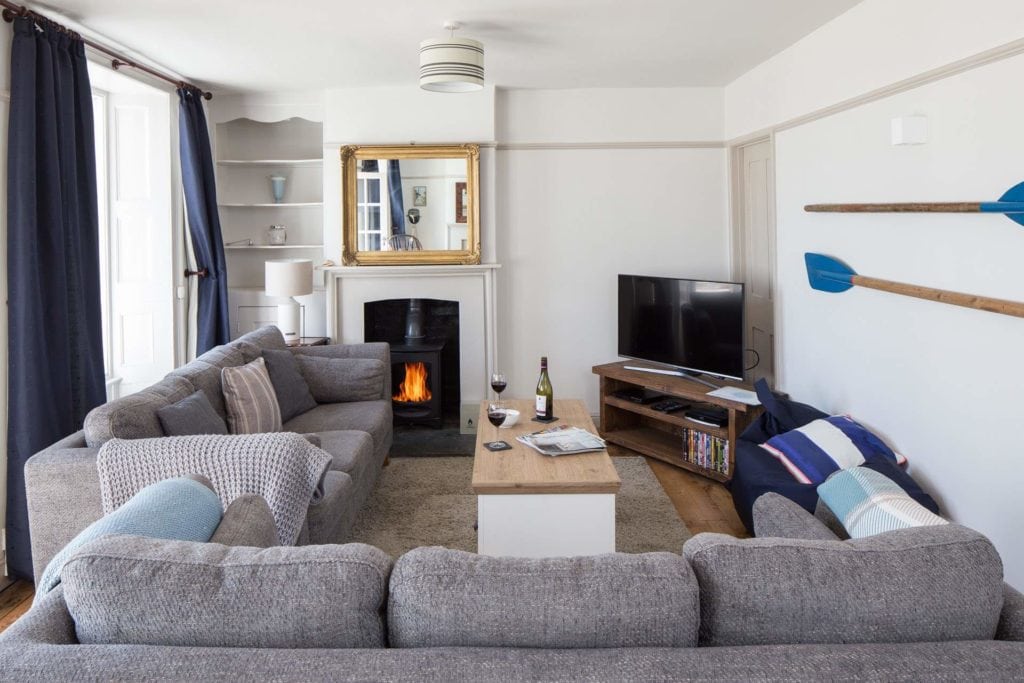 lounge with white walls and two light grey three seater sofas. there is a tv in the right corner and two oars mouted on the right side wall. Best Holiday Cottages in Dorset