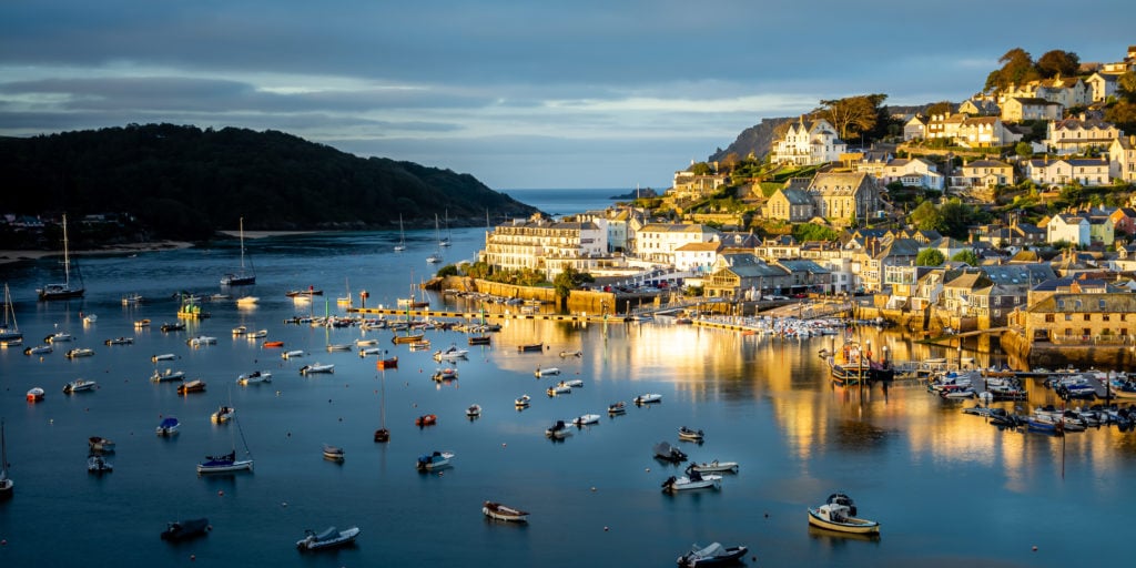 Sunrise over Salcome Town in south Devon - taken from Snapes Point looking across a very calm, flat river with many yachts moored in it towards the small hill with the small town of Salcombe on. best day trips from dorset. 