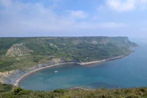 View from a cliff top of a semi circular cove surrounded by tall grassy cliffs. Chapman's Pool walk.
