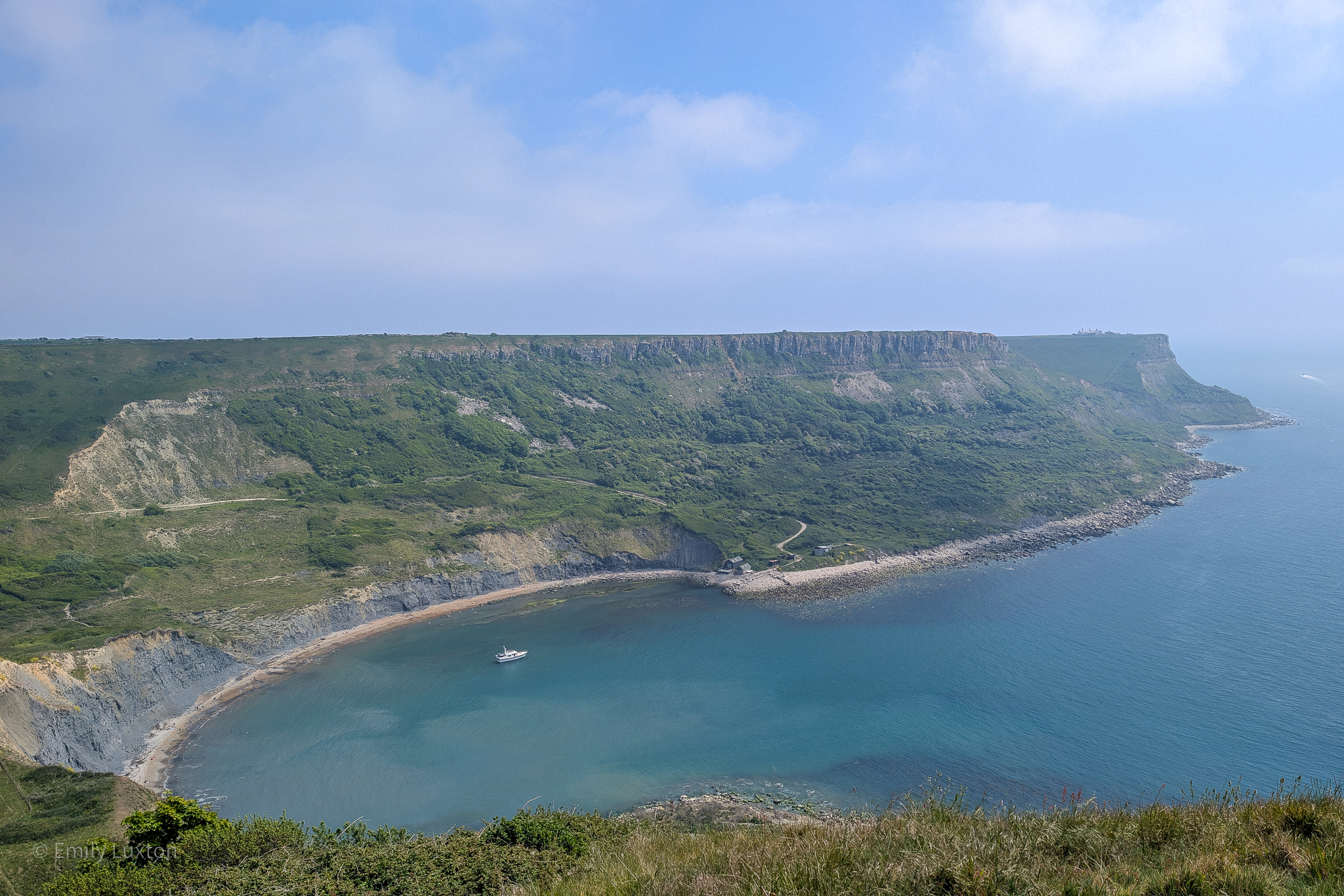 View from a cliff top of a semi circular cove surrounded by tall grassy cliffs. Chapman's Pool walk.