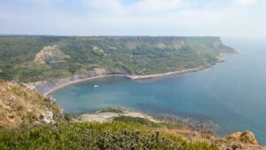 View from a cliff top of a semi circular cove surrounded by tall grassy cliffs. Chapman's Pool walk.