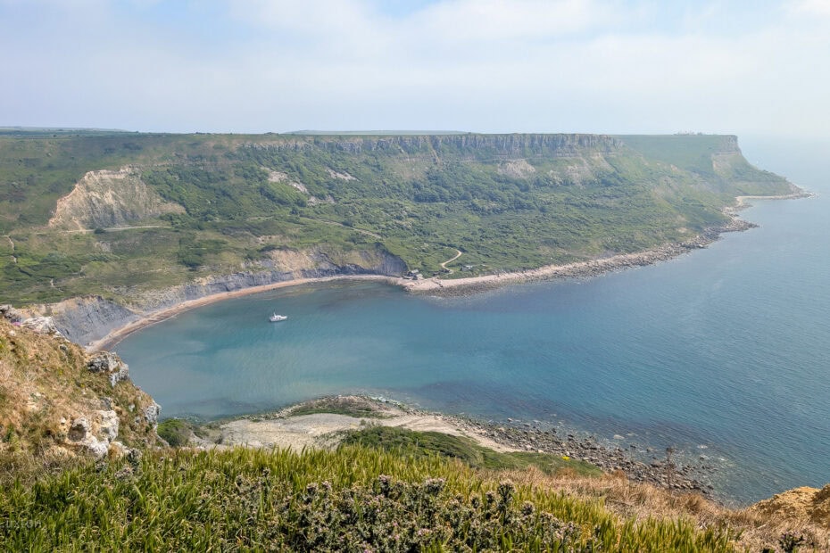 View from a cliff top of a semi circular cove surrounded by tall grassy cliffs. Chapman's Pool walk.