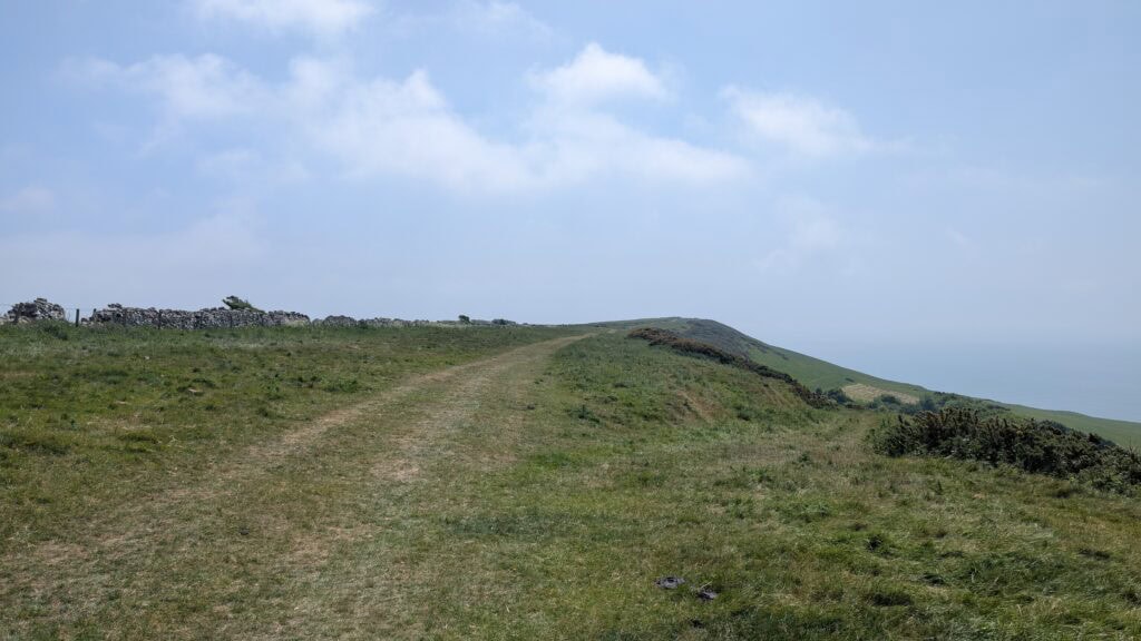 Grassy path along the top of a ridge with blue sky above. 