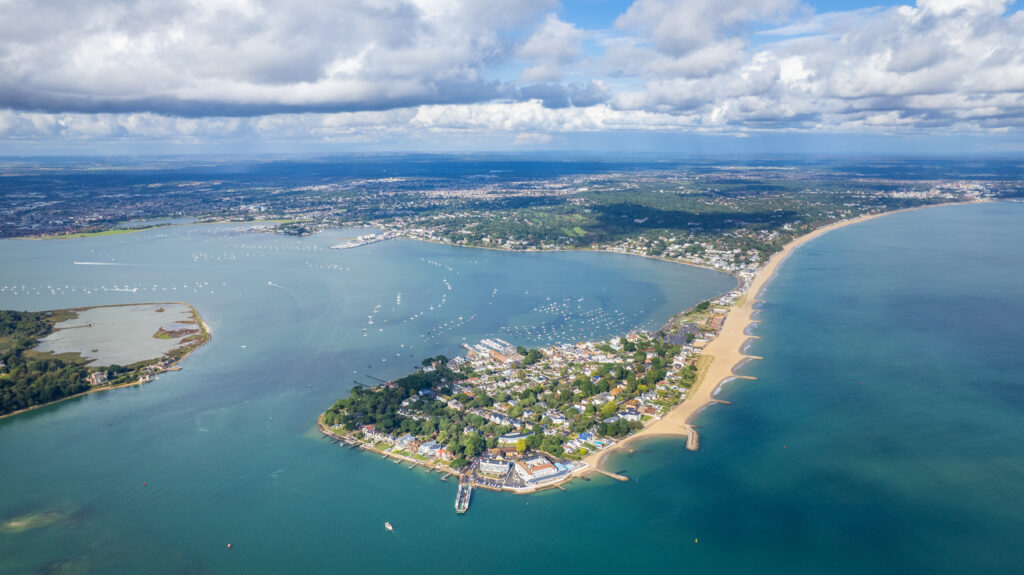 aerial panorama view of Sandbanks peninsula with a long white sandy beach along one side and blue sea on either side
