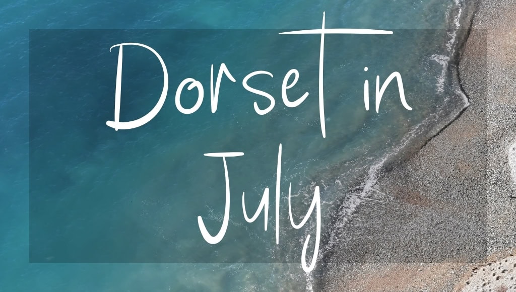 Dorset in July: written in white over an aerial photo of the sea on a sunny day