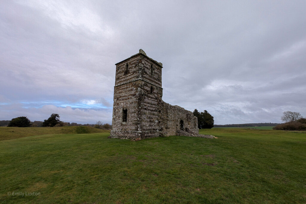 ruined stone church in a field with grey sky behind