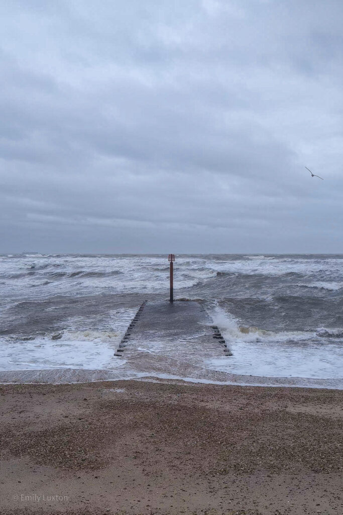 stone jetty with crashing waves during a storm