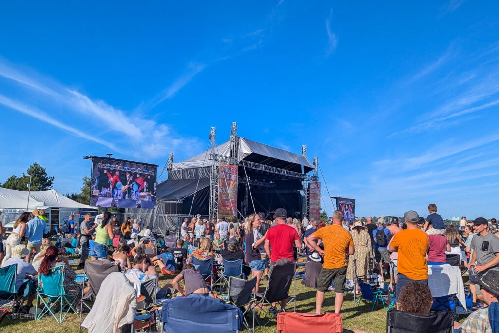 Crowd at a festival in front of an outdoor stage on a sunny day