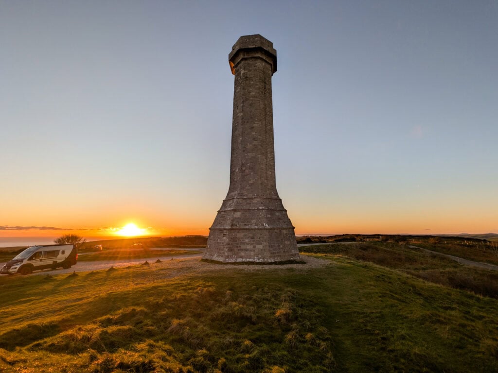sunset next to a tall stone tower on a hilltop