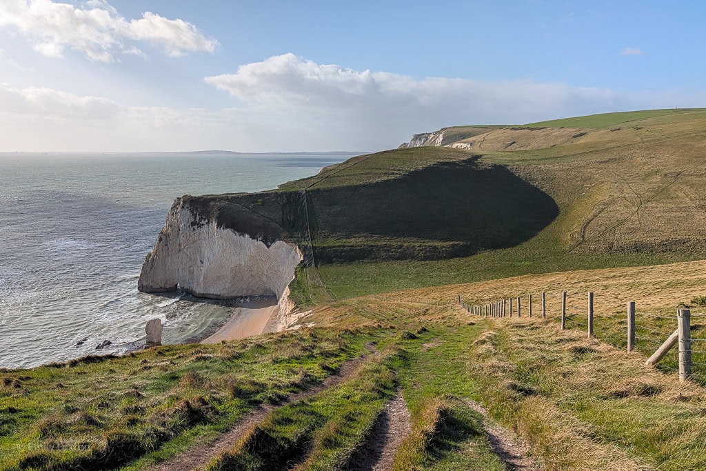 View of a grassy coast path leading towards a white chalk headland | Ringstead to Durdle Door walk